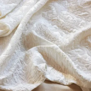 SDH Jasmine Matelasse duvet cover in ivory with floral quilted texture, draped.