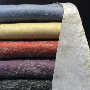 Leitner Tratten herringbone decorative pillows stacked in six colors including slate, gold, rust, plum, and charcoal.